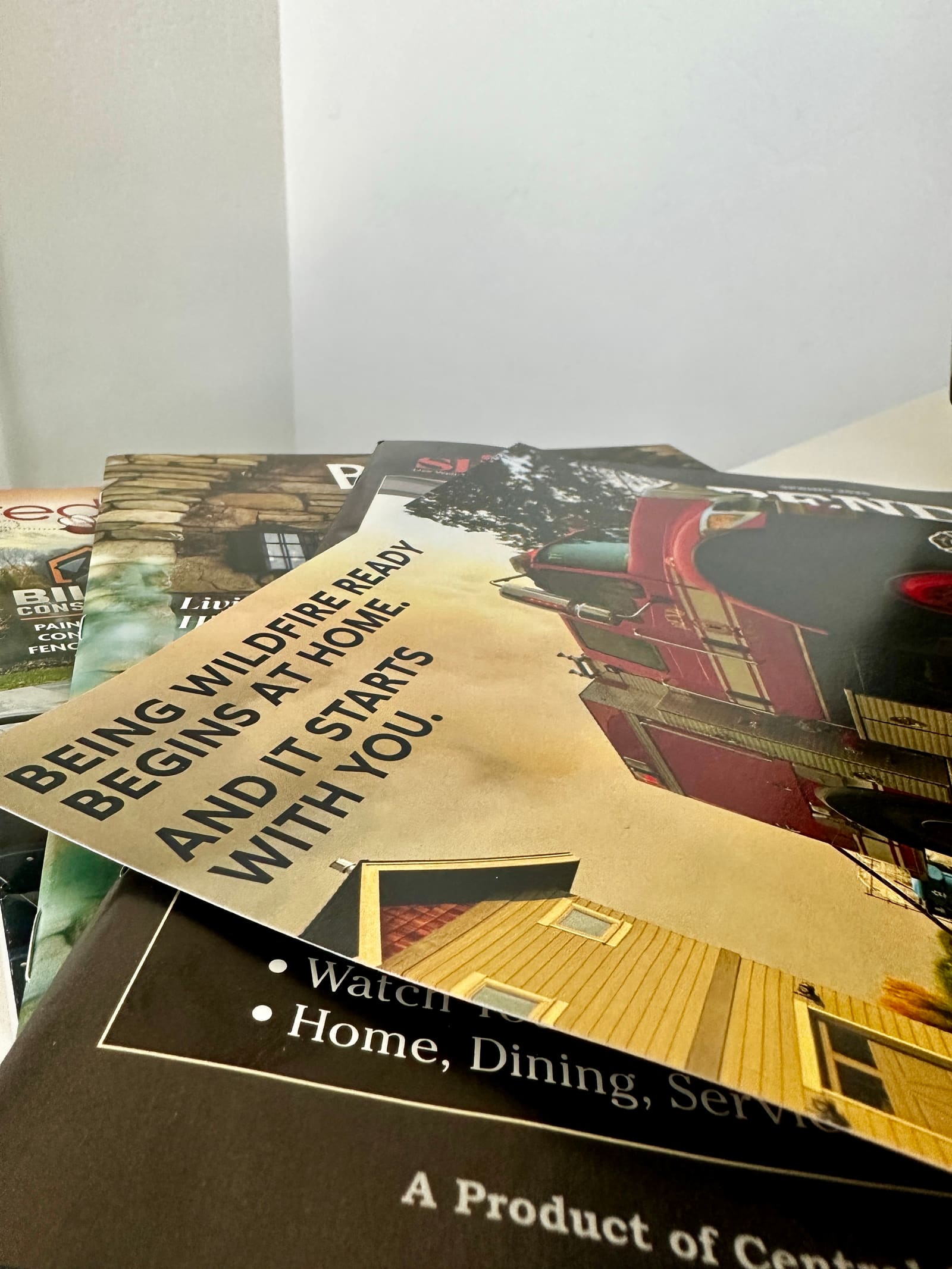 A pile of glossy local print mailers, magazines, and flyers stacked on top of each other